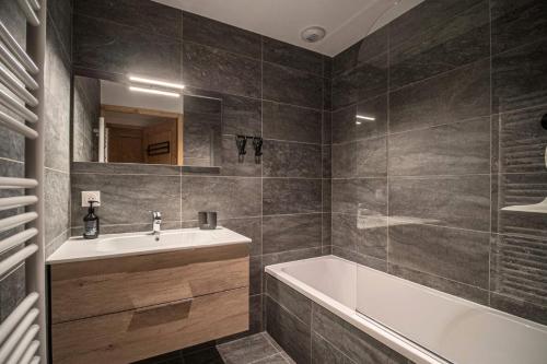 une salle de bain avec une baignoire et un lavabo et une baignoire dans l'établissement Résidence Lumi Batiment B - LUMI B ALPAGA 306 MAE-7221, à Valmorel