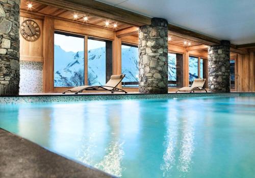 - une piscine avec 2 chaises et une horloge dans l'établissement Les Chalets Du Gypse - LES CHALETS DU GYPSE A05 MAE-3471, à Saint-Martin-de-Belleville