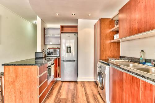 a kitchen with wooden cabinets and a stainless steel refrigerator at Rockwell Views in Cape Town