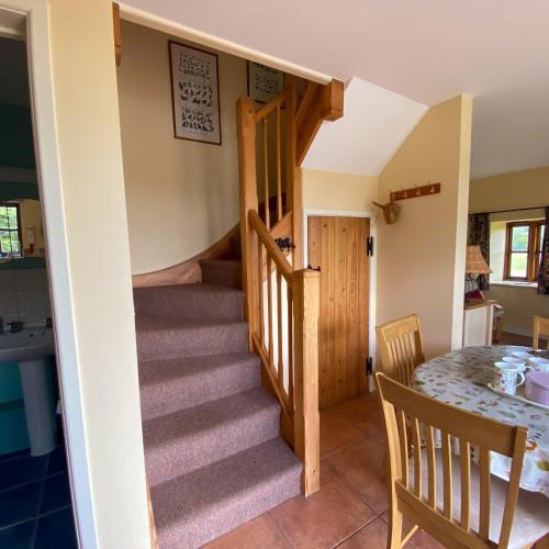 a view of the dining room and kitchen with the stairs leading up to the loft at Red Tiles Barn in Evercreech