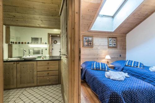 - une chambre avec un lit bleu et une salle de bains dans l'établissement Les Chalets Du Gypse - LES CHALETS DU GYPSE C15 MAE-3691, à Saint-Martin-de-Belleville