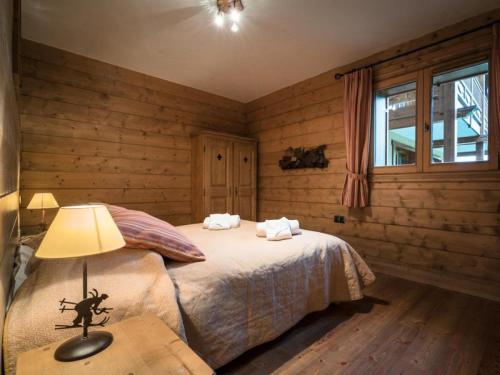 - une chambre avec des murs en bois et un lit avec une lampe dans l'établissement Les Chalets Du Gypse - LES CHALETS DU GYPSE C03 MAE-3741, à Saint-Martin-de-Belleville