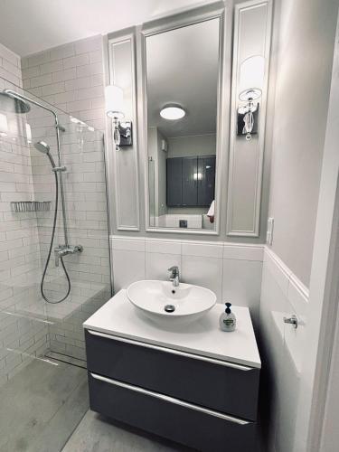 a white bathroom with a sink and a shower at Apartament WHITE GLOVE Deluxe Warmiński Port in Olsztyn