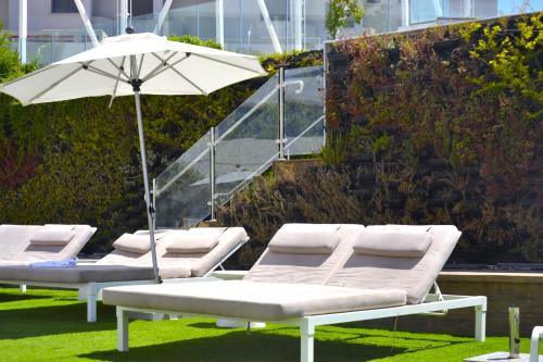 a row of lounge chairs with an umbrella at סי סייד, אילת - סמואל - Sea Side Eilat in Eilat