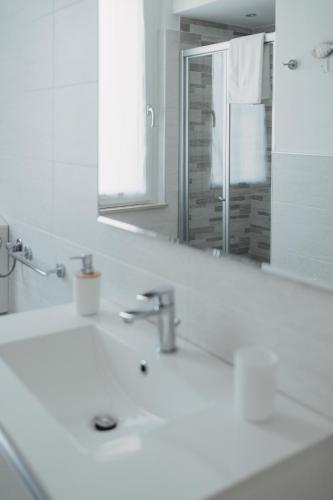 a white bathroom with a sink and a mirror at Casa degli Ulivi - Apartment B in Porto San Giorgio