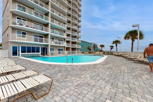 a man walking by a swimming pool next to a building at Tradewinds 501 in Orange Beach