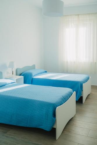 three beds in a room with blue sheets at Casa degli Ulivi - Apartment B in Porto San Giorgio