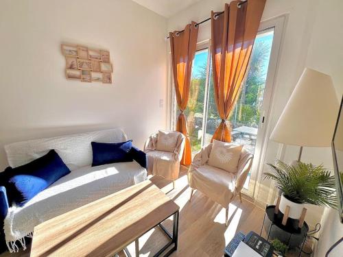 un salon avec un canapé, des chaises et une fenêtre dans l'établissement Maison lumineuse à LOCTUDY, à Plobannalec-Lesconil