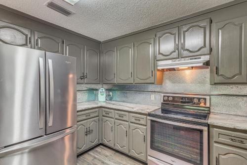 a kitchen with white cabinets and a stainless steel refrigerator at Riverfront Milton Cabin with Boat Ramp and Dock! in Milton