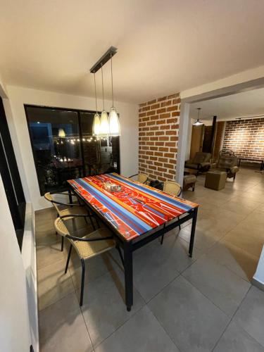a dining room table with chairs and a brick wall at Habitación con baño privado en casa de campo ubicada en Santa Elena in Santa Elena