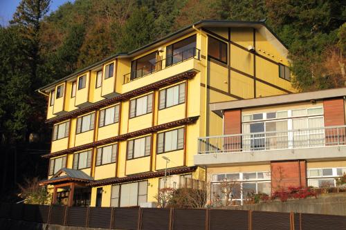 a large yellow building with a fence in front of it at Hotel Asafuji in Fujikawaguchiko