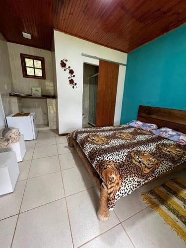 a bedroom with a bed with a leopard print blanket at Chalé no Sana - Equilíbrio e Descanso in Sana