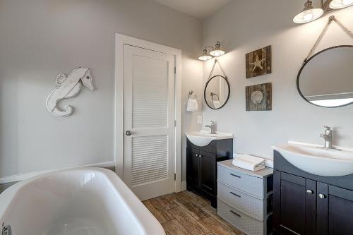 a bathroom with a tub and two sinks and a mirror at The Pearl of Port A GW108 in Port Aransas