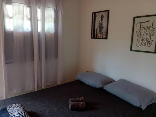 a bedroom with a bed with two pillows and a window at Chalé Romântico no Sana - Aconchego e Conforto in Sana