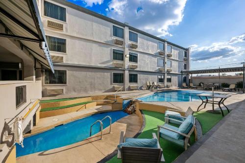 an apartment building with a swimming pool and patio furniture at SureStay Plus Hotel by Best Western Lubbock Medical Center in Lubbock