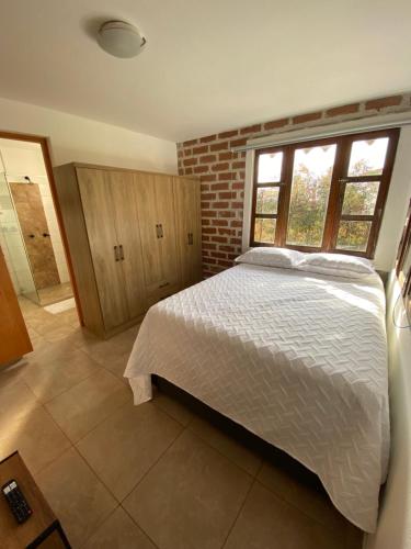 a bedroom with a white bed and a brick wall at Habitación con baño privado en casa de campo ubicada en Santa Elena in Santa Elena