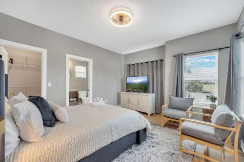 ein Schlafzimmer mit einem Bett, einem Fernseher und einem Stuhl in der Unterkunft NEWLY BUILT SMV Oceanview Terrace House in Jacksonville Beach