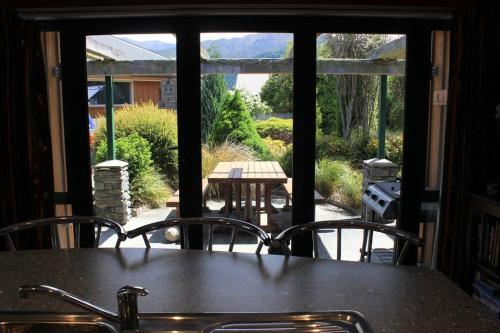 a table and chairs with a view of a patio at Popular Family and Pet friendly Modern Cosy Bach WiFi in Hanmer Springs