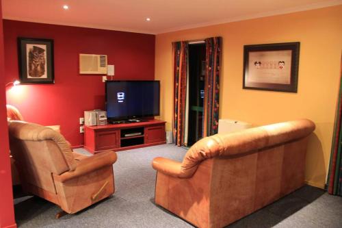 a living room with two chairs and a flat screen tv at Popular Family and Pet friendly Modern Cosy Bach WiFi in Hanmer Springs