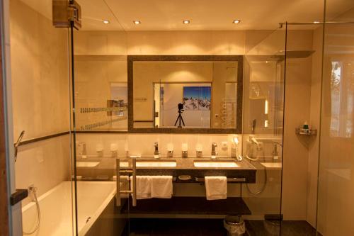 a bathroom with a sink and a mirror and a tub at Alpenresidenz Trisanna in Ischgl