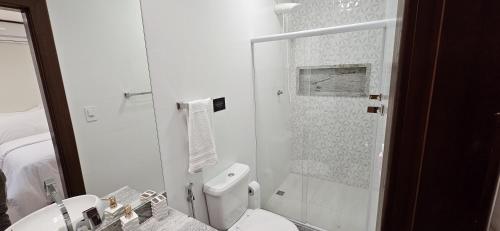 a white bathroom with a toilet and a shower at Casa Boa Vista in Cachoeiro de Itapemirim