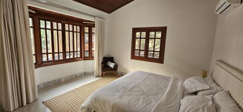 a bedroom with a bed and two windows at Casa Boa Vista in Cachoeiro de Itapemirim