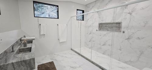 a white bathroom with a shower with a glass door at Casa Boa Vista in Cachoeiro de Itapemirim