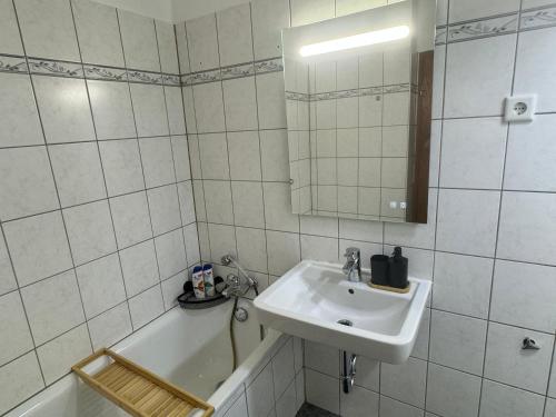 Un baño de azulejos blancos con lavabo y bañera. en Stylish & Relaxing Modernes Apartment mit Privatparkplatz, en Gelsenkirchen