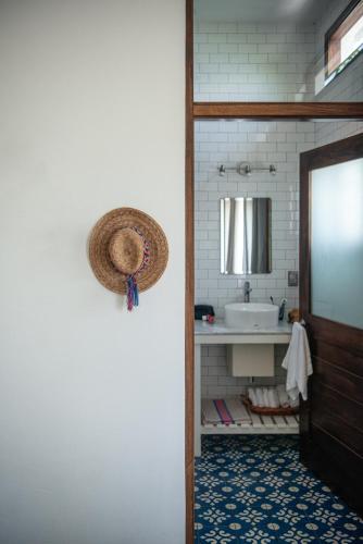 a bathroom with a sink and a straw hat on the door at Casa Kalmar in Zipolite