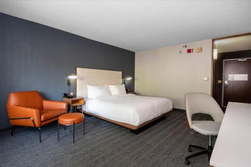 a hotel room with a bed and a desk and chair at Courtyard Columbus Airport in Columbus