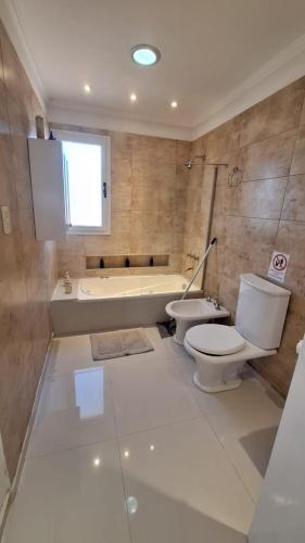 a bathroom with a toilet and a bath tub at Cabañas Terruños de Pilar in Malargüe
