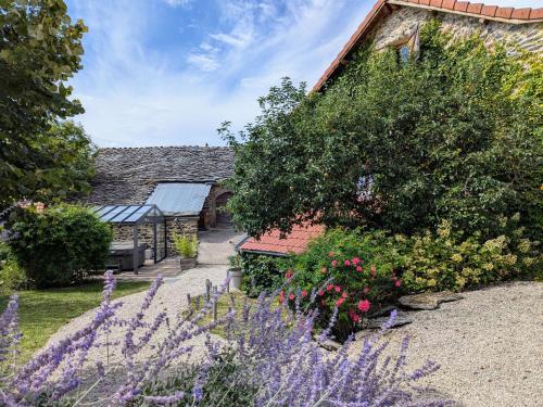 a garden with flowers in front of a building at Gîte d'exception avec spa, jardin paysagé et équipements haut de gamme à Blanlhac - FR-1-582-201 in Rosières