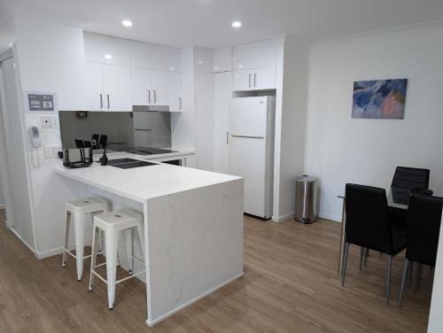 a white kitchen with a counter and stools at Bay Lodge Apartments in Gold Coast