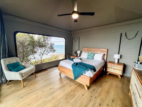 a bedroom with a bed and a chair and a large window at Lorne Foreshore Caravan Park in Lorne