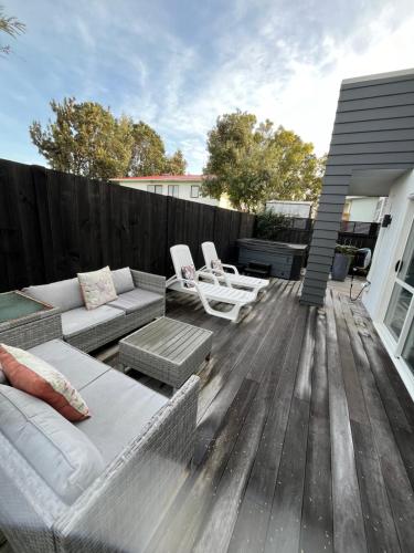 a patio with couches and chairs on a wooden deck at Papamoa Family Beach House in Tauranga