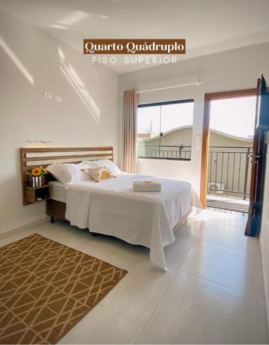 a bedroom with a white bed and a large window at Pousada Villa Vantino in Penha