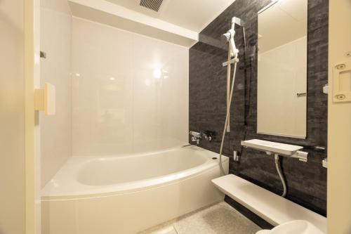 a bathroom with a tub and a toilet and a sink at Kushiro Century Castle Hotel in Kushiro