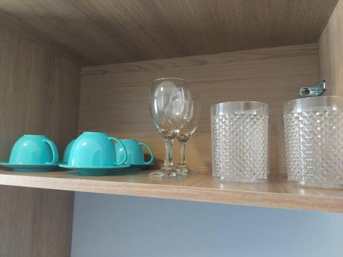 a shelf with glasses and plates and a wine glass at Charmoso ap em Sete lagoas in Sete Lagoas