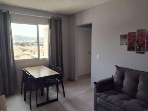 a living room with a couch and a table and a window at Charmoso ap em Sete lagoas in Sete Lagoas