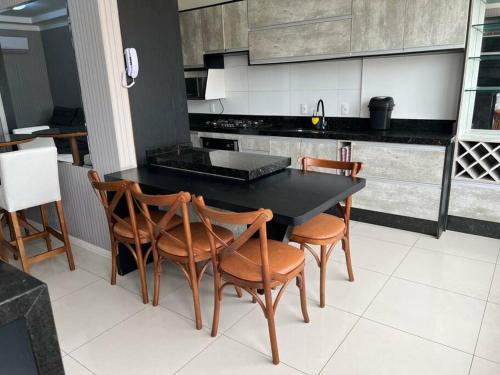 a kitchen with a black table and wooden chairs at Apartamento Porto Belo - Perequê in Perequê