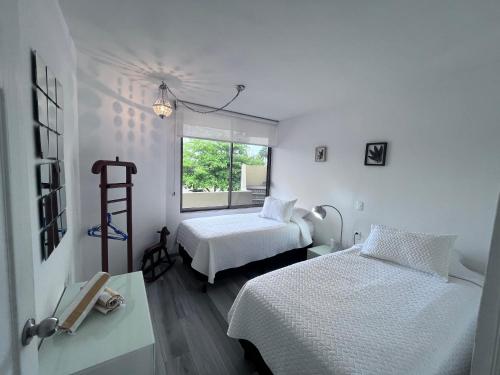 a white room with two beds and a window at Oceanfront Condo at Unique Location in Cancún
