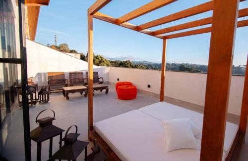 a balcony with a bed and a table and chairs at Room Hotel Wanderlust in Campos do Jordão