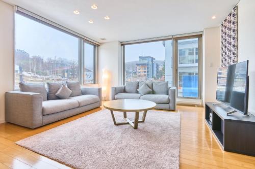 a living room with a couch and a tv and a table at Niseko Central Condominiums in Kutchan