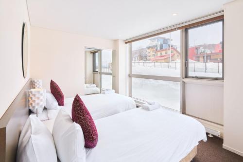 two beds in a room with a large window at Niseko Central Condominiums in Kutchan