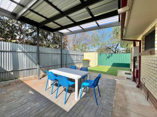 a patio with a white table and blue chairs at Payneham South Paradise Suite 4 in Norwood