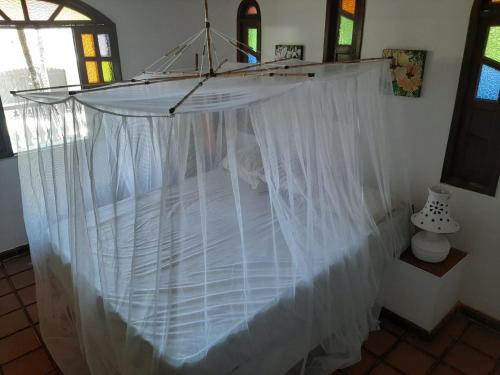a bed with a white canopy in a room at Casa Ilha de Itaparica Bahia in Ilha de Itaparica