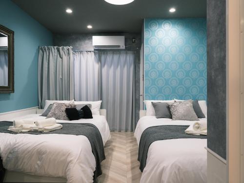 two beds in a room with blue walls at Tsubame INN Nipponbashi in Osaka
