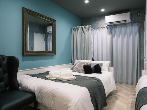 a bedroom with two beds with a mirror and a chair at Tsubame INN Nipponbashi in Osaka