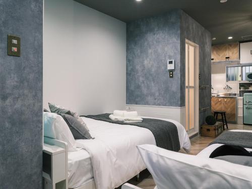 a bedroom with two beds and a kitchen at Tsubame INN Nipponbashi in Osaka