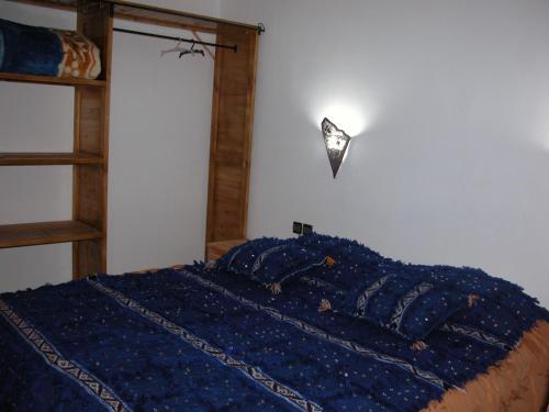 a bedroom with a bed with a blue blanket at Kasbah Petit Nomade in Tinerhir